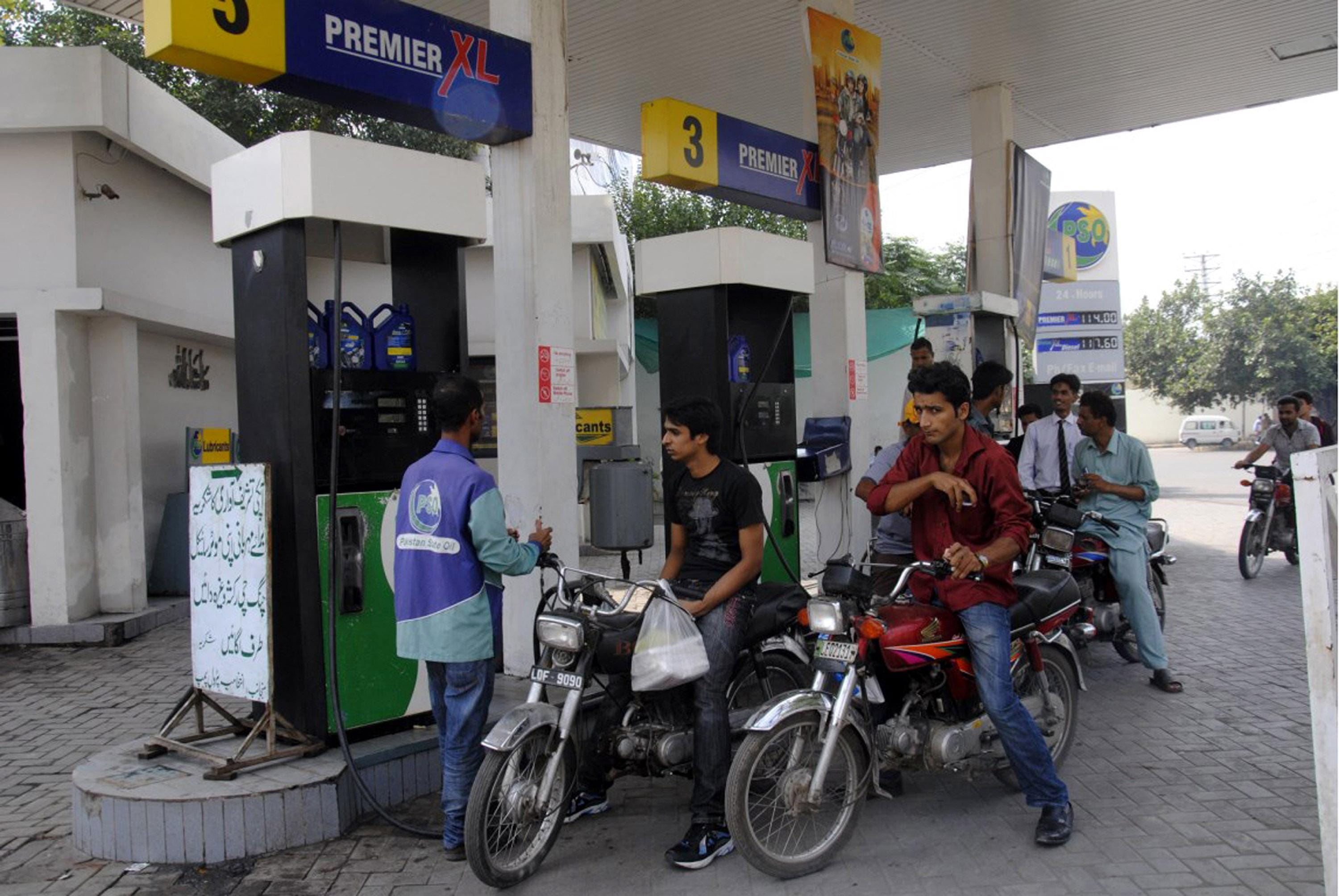 A gas station worker fills motorbikes with petrol at a gas station in eastern Pakistan
