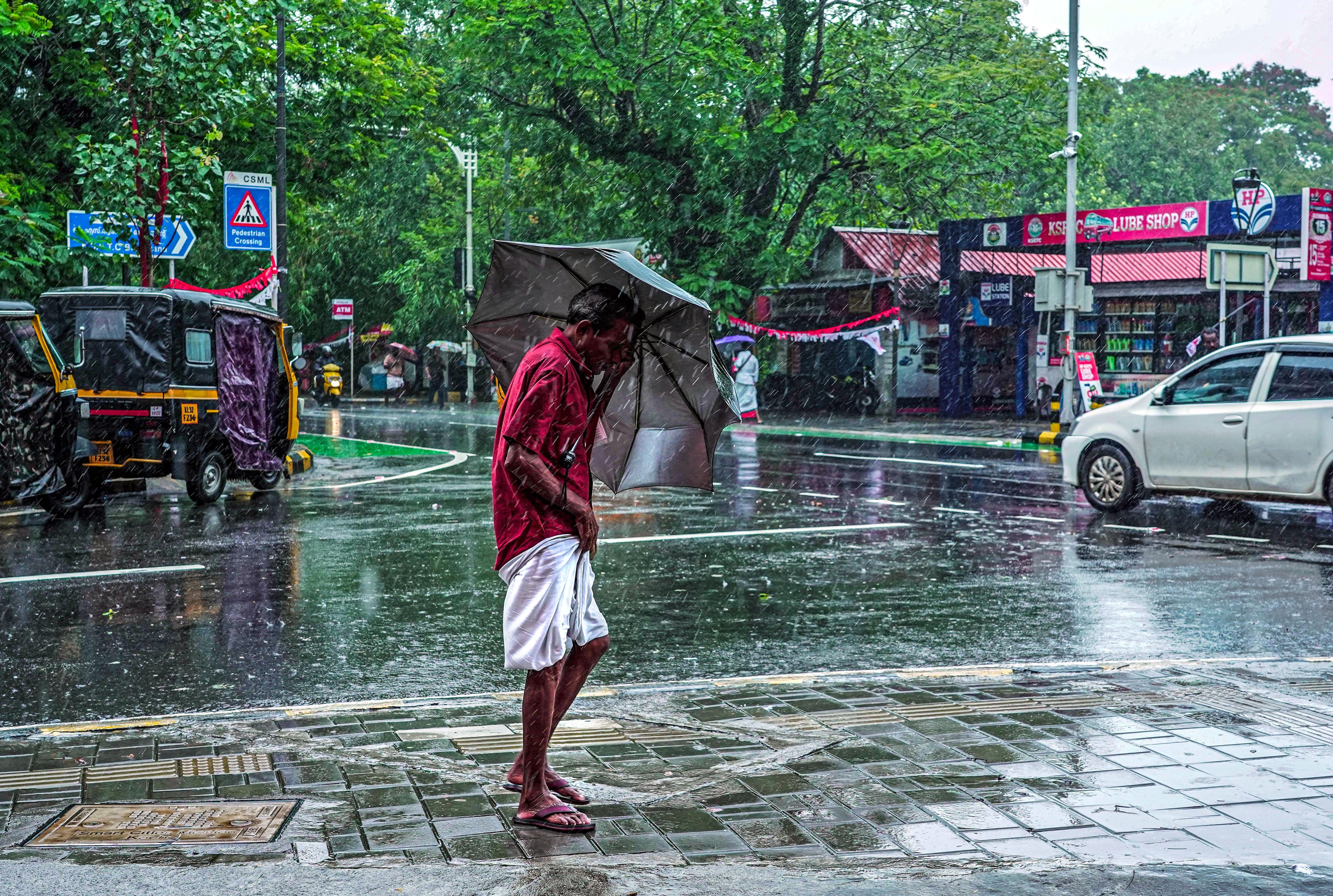 Kochi : A man walks under an umbrella amid heavy rainfall
