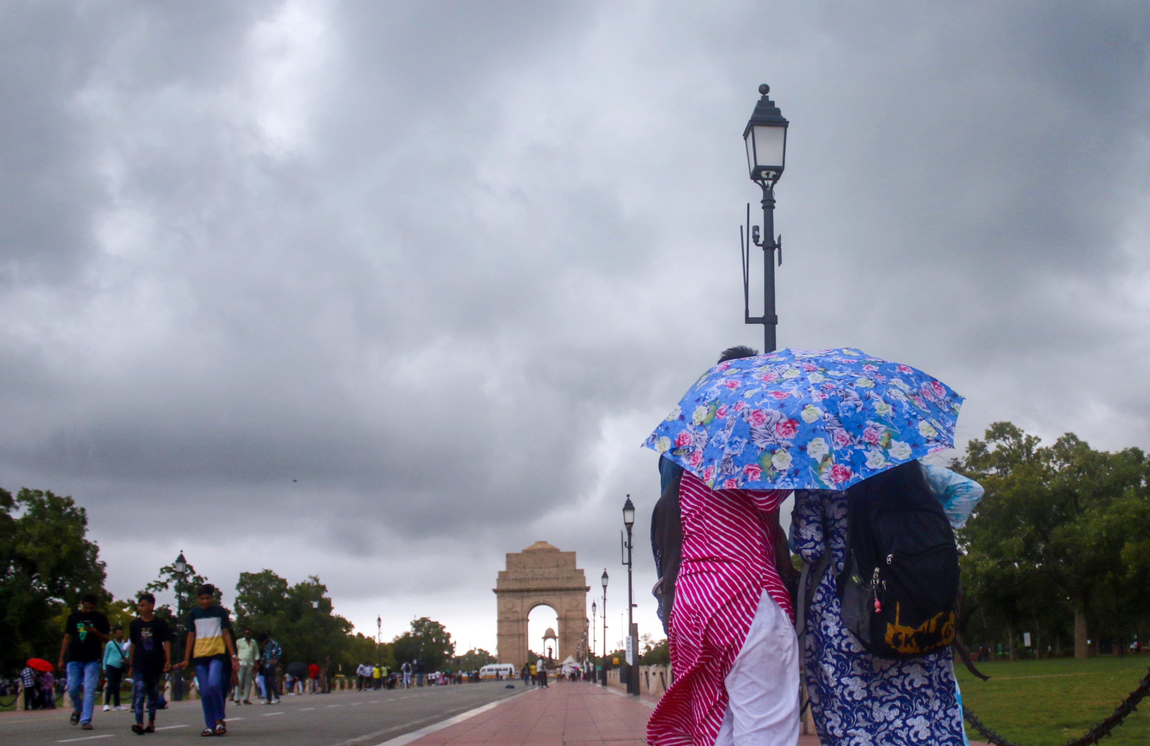 New Delhi: Commuters stroll at India Gate as clouds hover in the sky